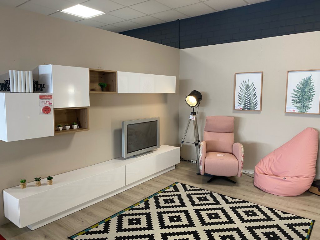 Salón con mueble moderno minimalista color blanco y butacas color rosa con gran alfombra de rombos