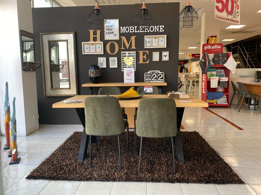 Mesa de comodor de madera maciza, patas metálicas negras y cómodas sillas tapizadas sobre alfombra